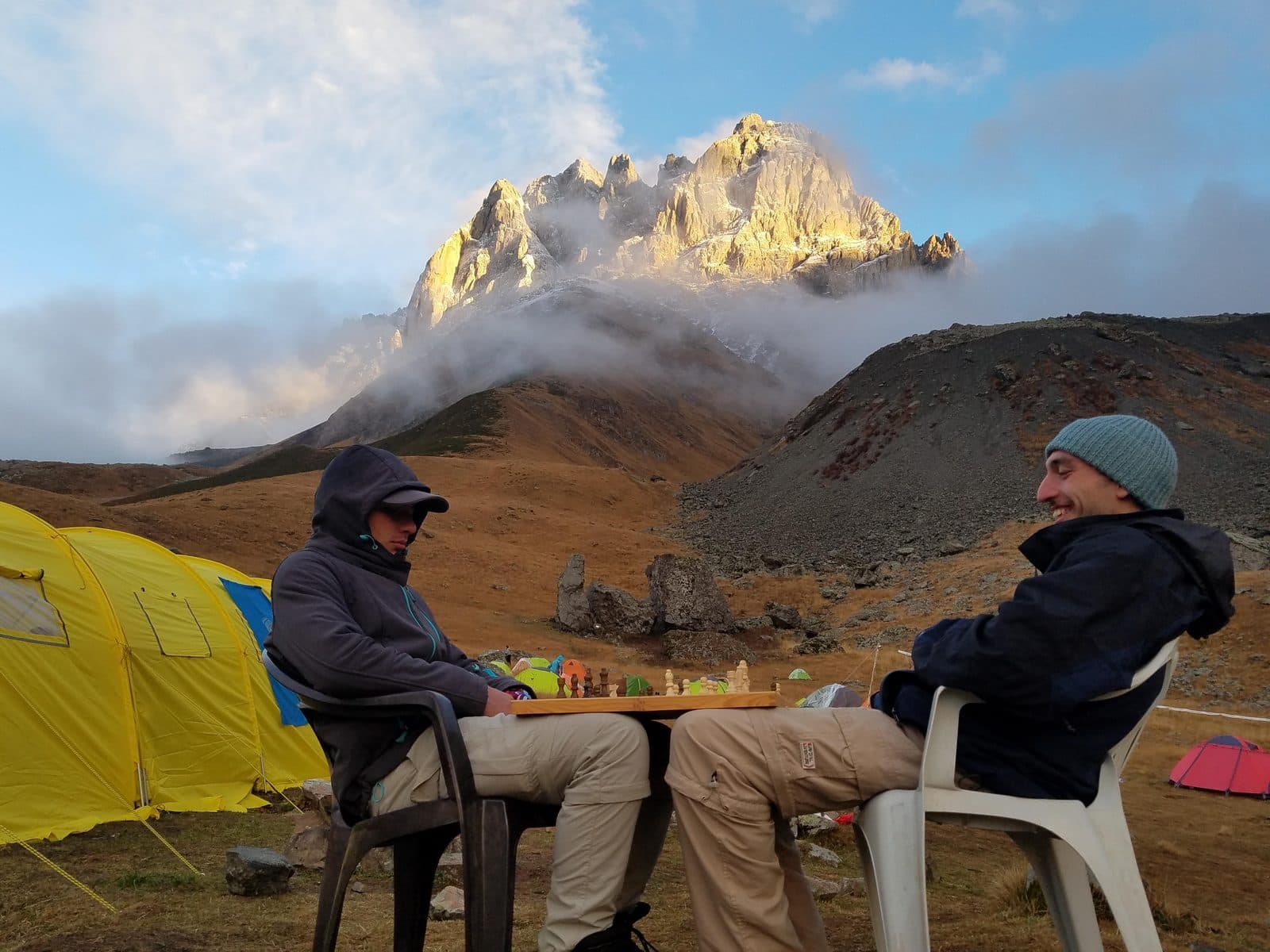 Two of the founders sitting at a camp table below a snow-capped peak in the Georgian Caucasus, October 2018