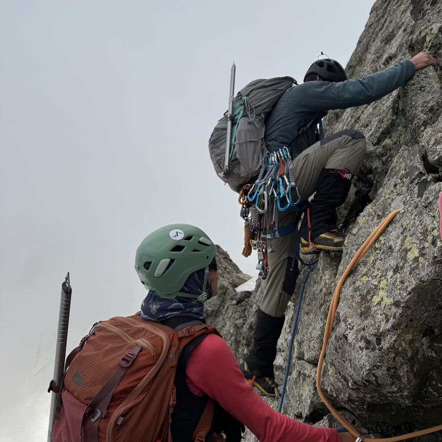Two climbers on a rock face with ropes, ice axes and technical gear