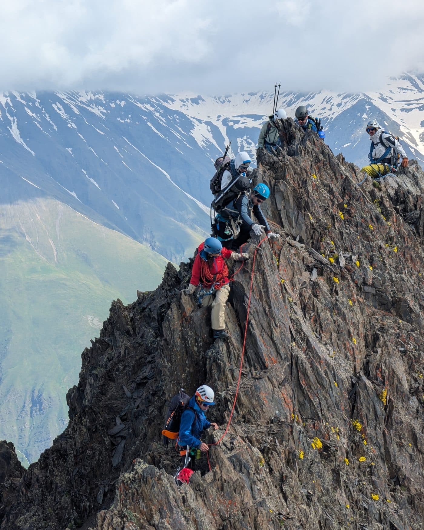 A roped team in helmets moving along a steep rocky ridge high in the Georgian Caucasus, June 2025