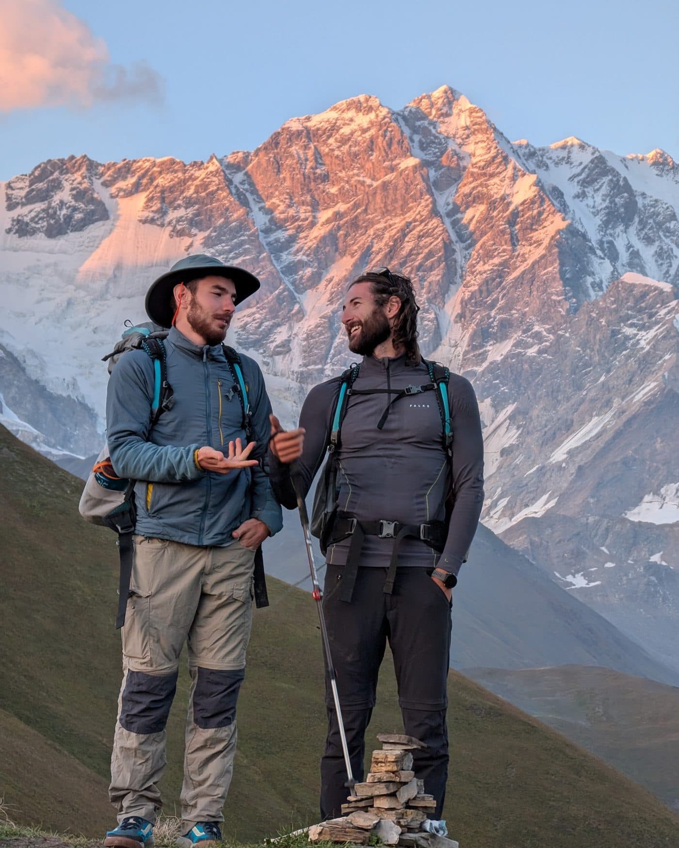 Two Adventure Experts Georgia founders talking on a ridge in front of a glaciated peak at sunset, August 2024
