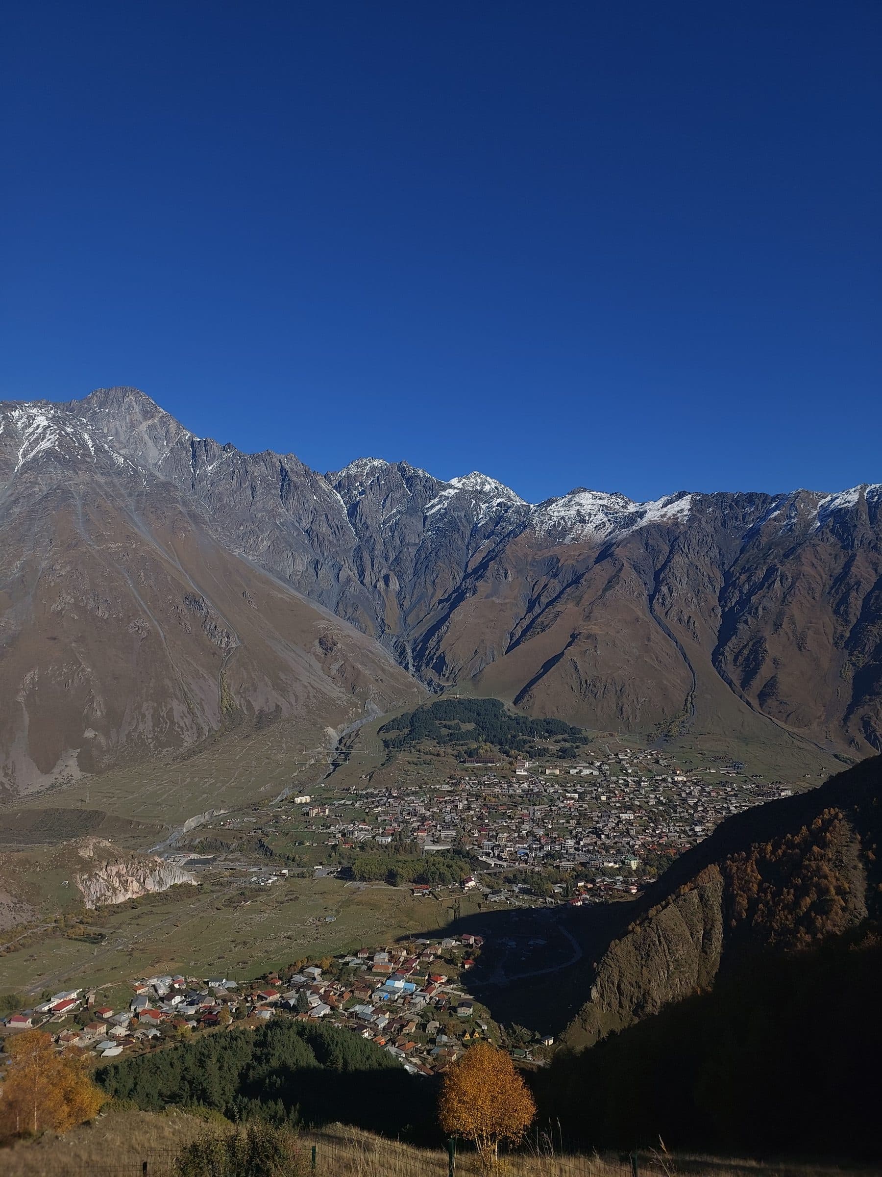 Stepantsminda (Kazbegi) town in the valley beneath snow-dusted Caucasus peaks