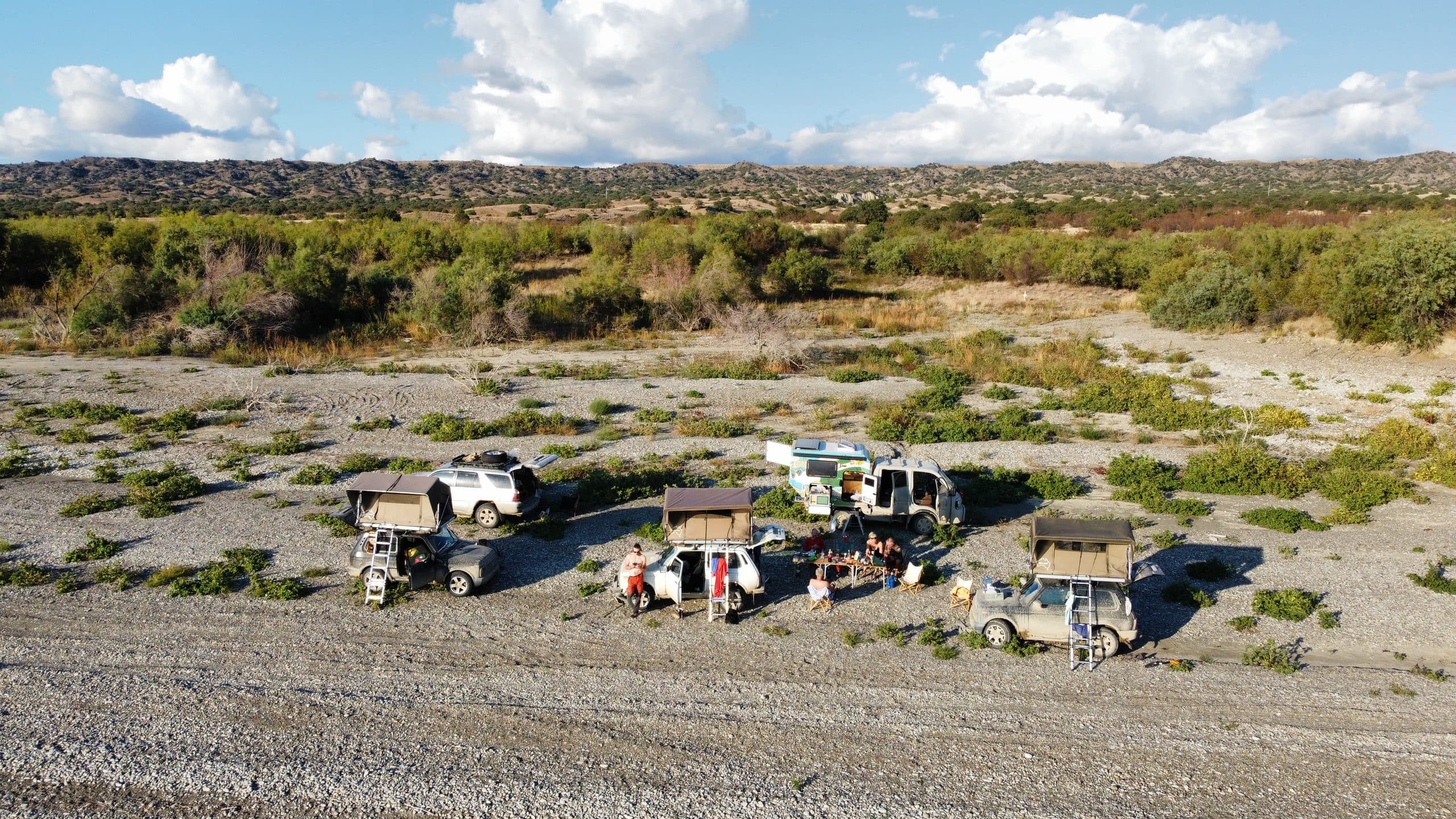 Overland camp with rooftop tents pitched at golden hour in a highland riverbed