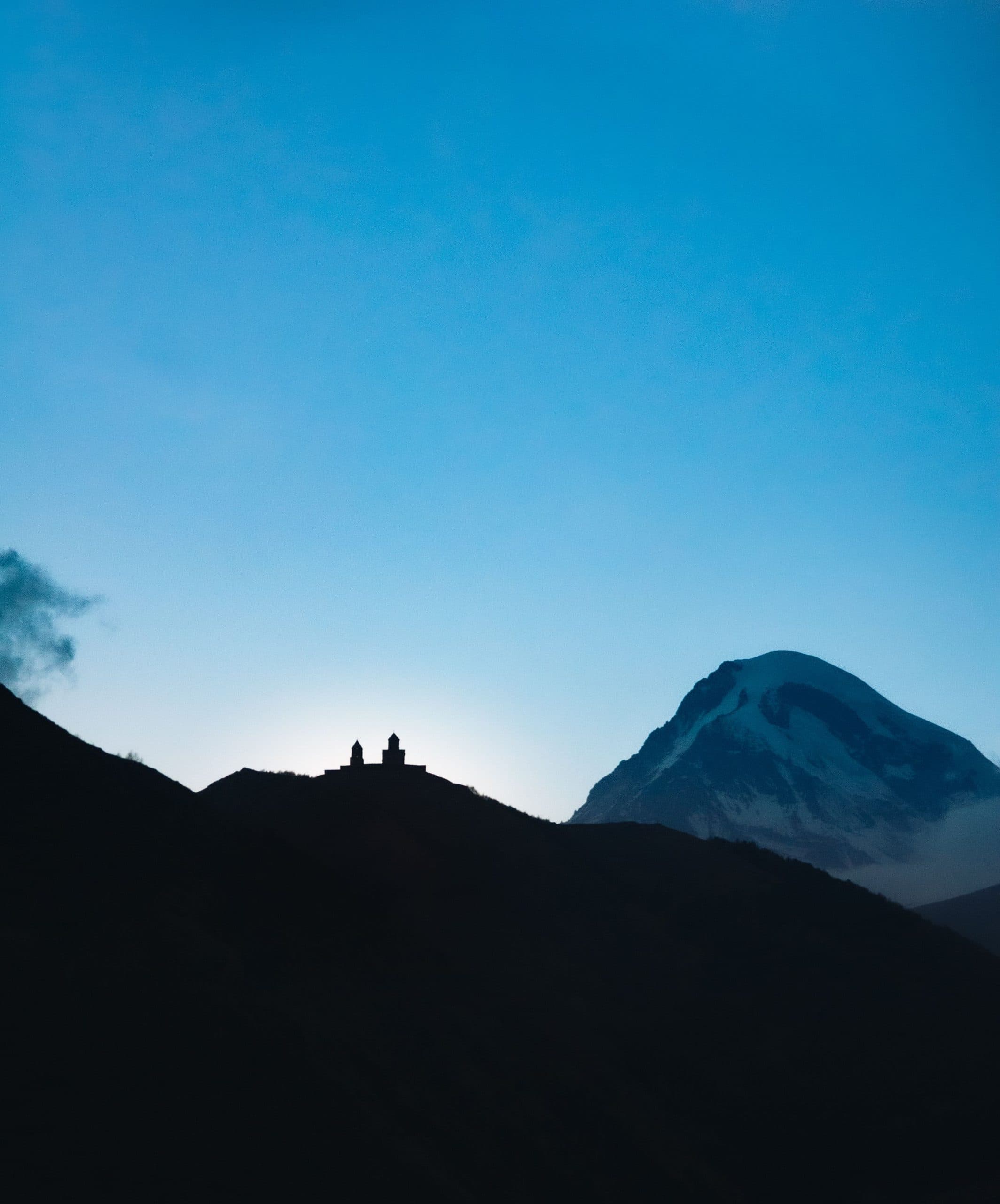 Gergeti Trinity Church silhouetted beneath Mount Kazbek at dusk