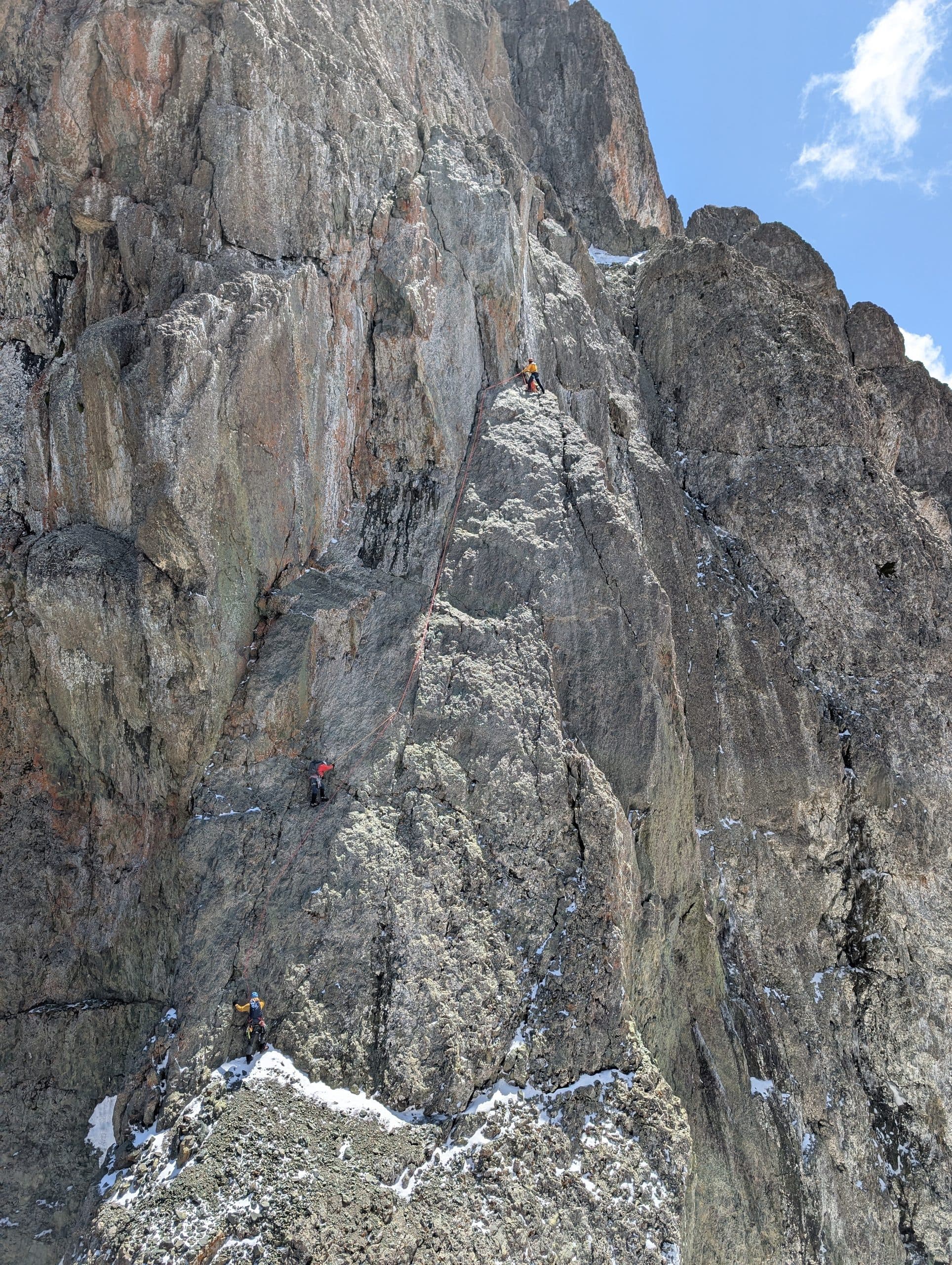Climbers dwarfed by the vertical rock of the Chaukhi Massif
