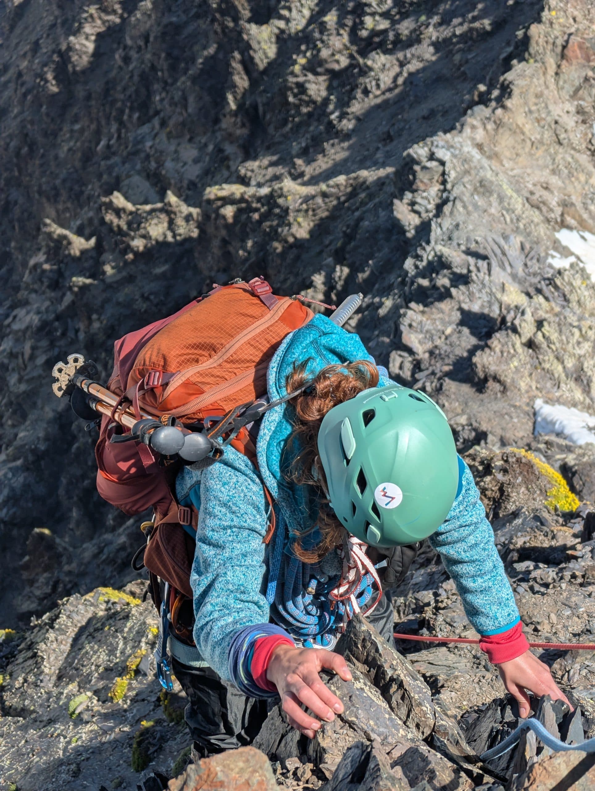 A climber moving over rock on the way to a summit